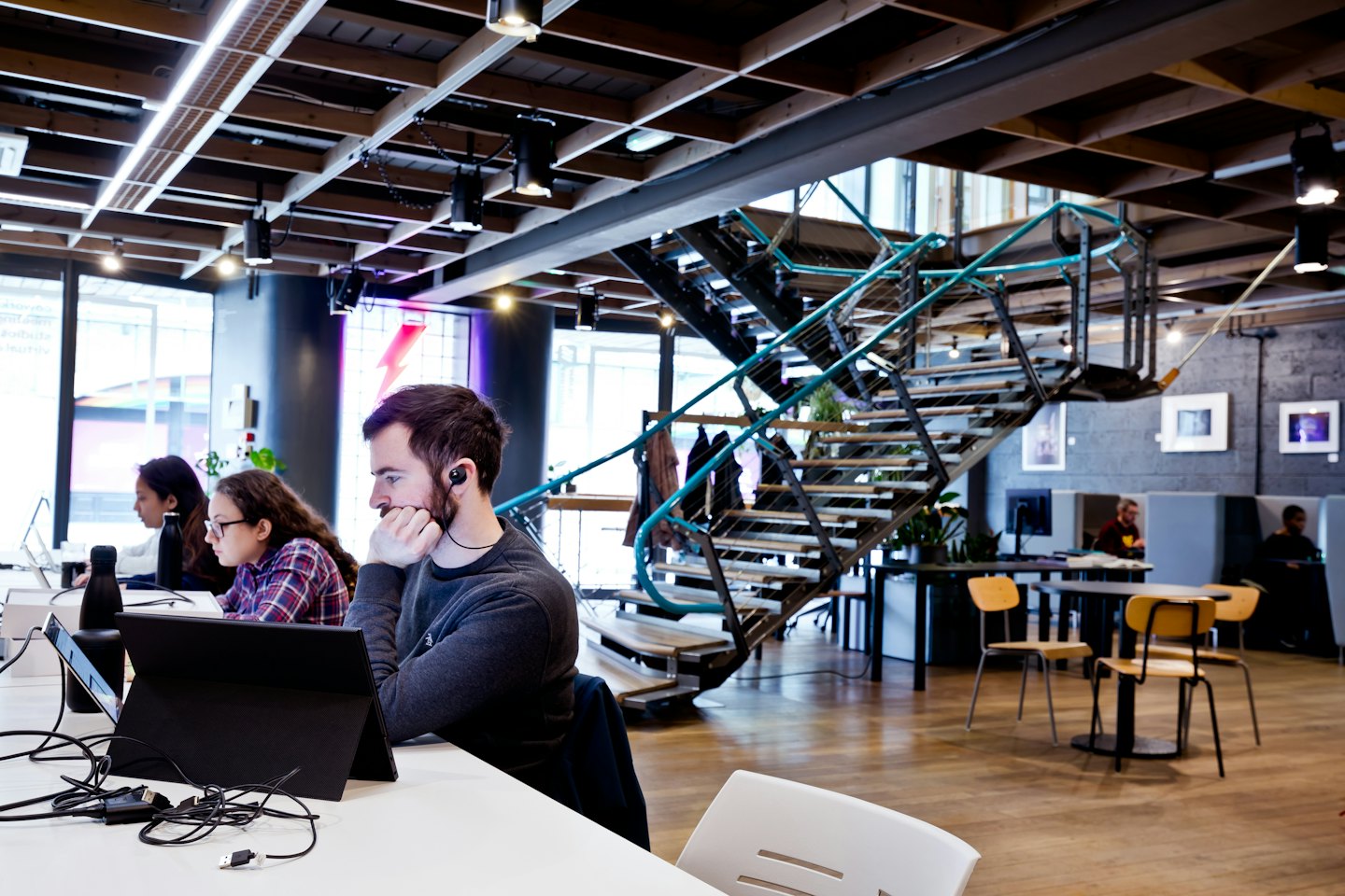 Three colleagues work on laptops in a modern industrial office.