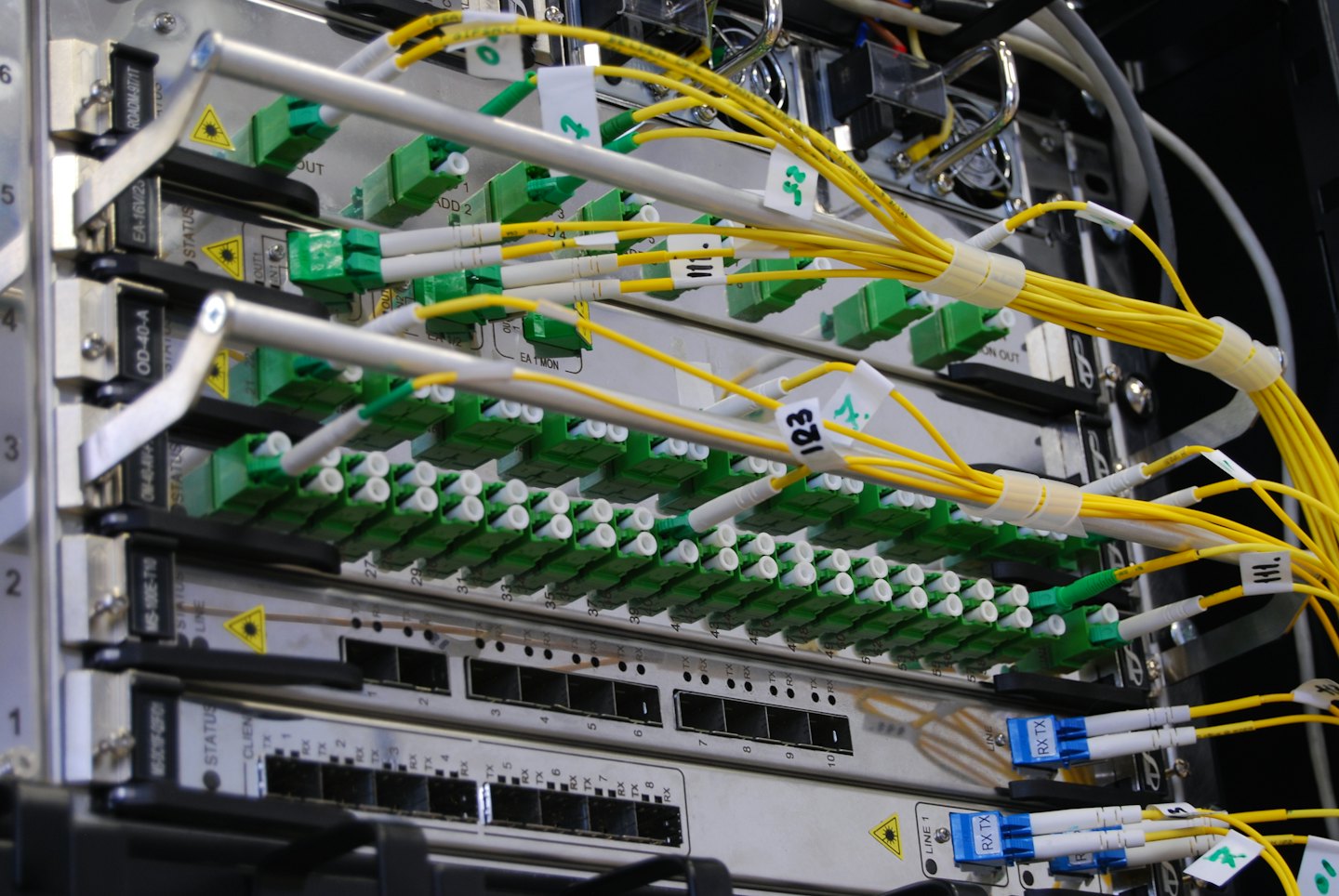 Bundles of yellow fiber optic cables connect to ports in a server rack.